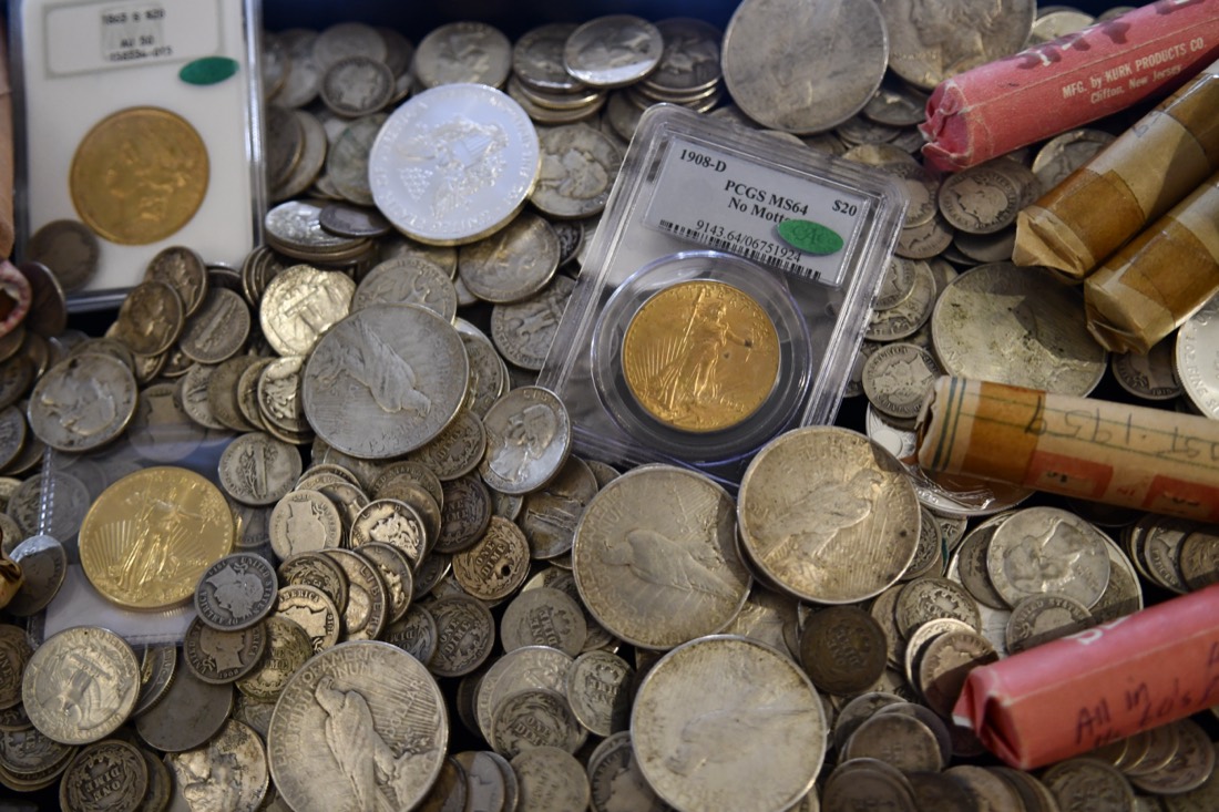 PCGS-graded gold coin with Peace dollars and coin rolls